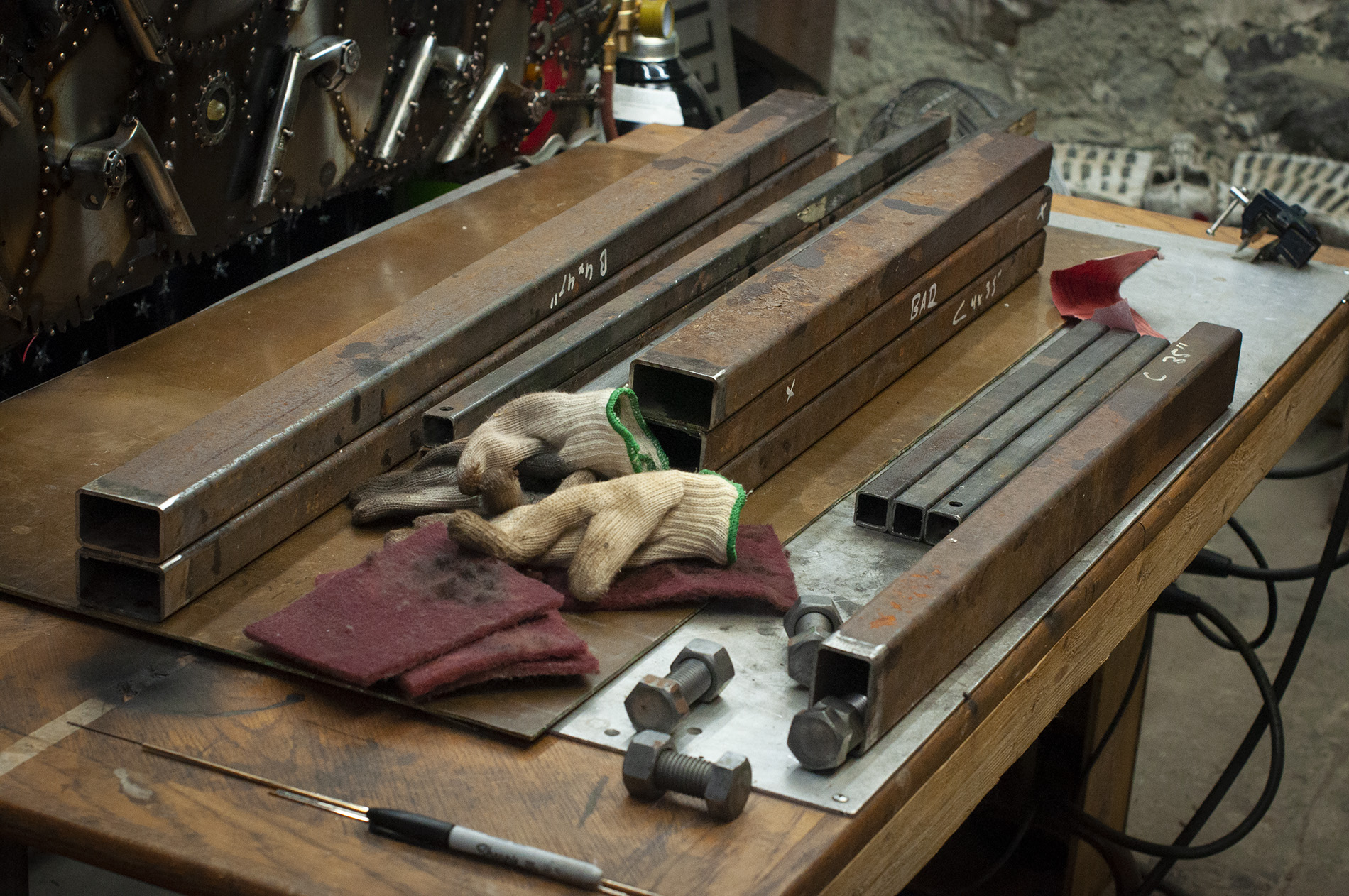 sturdy square steel stock lays on top of a silicon bronze plate, ready to weld into a weld table.