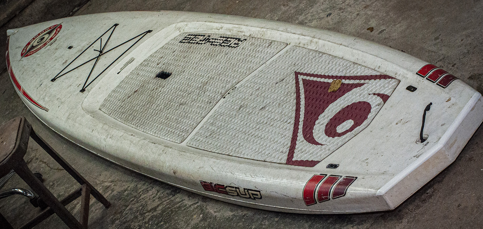 a very used and dirty standup paddleboard in a basement
