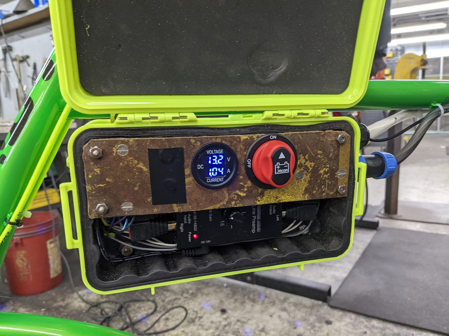 a green pelican case is open, showing a master power switch, a preamp, and a meter