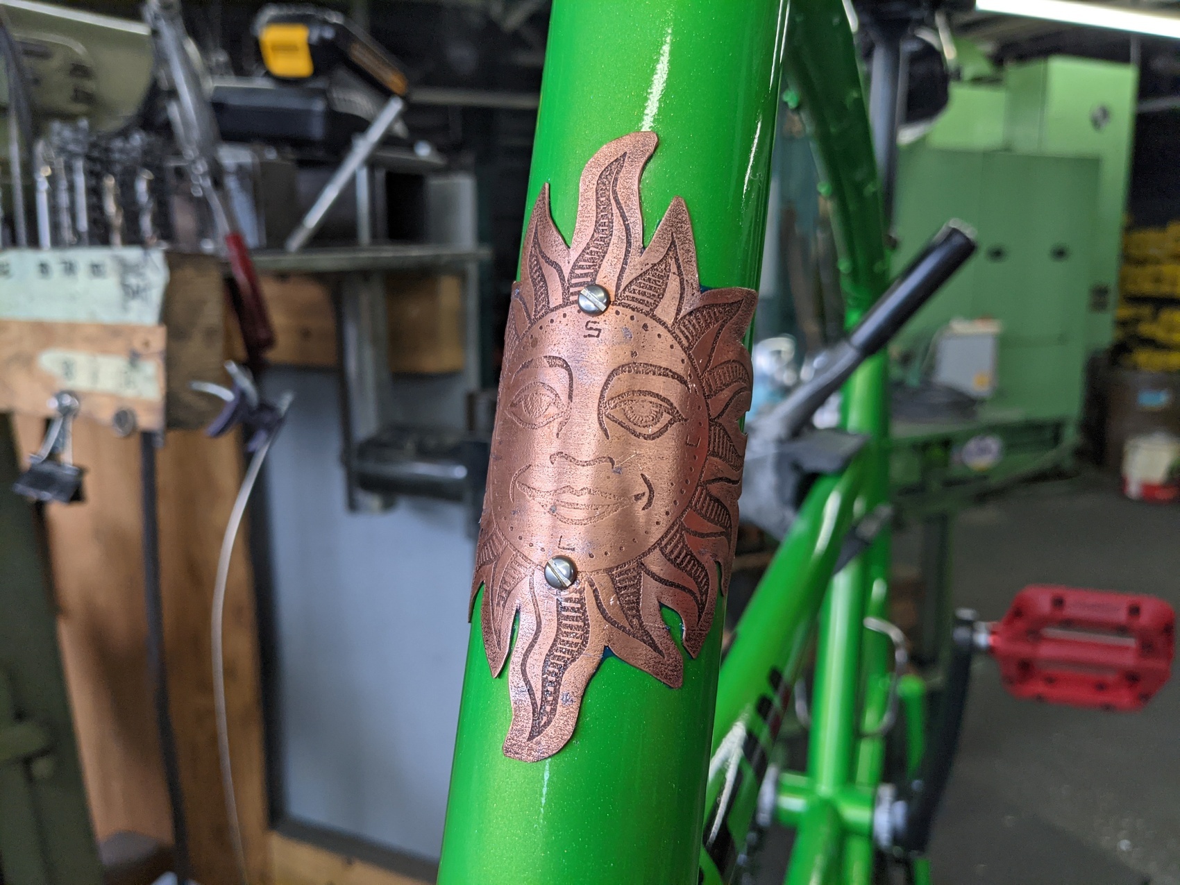 a copper sun headbadge on a sparkly green tallbike frame
