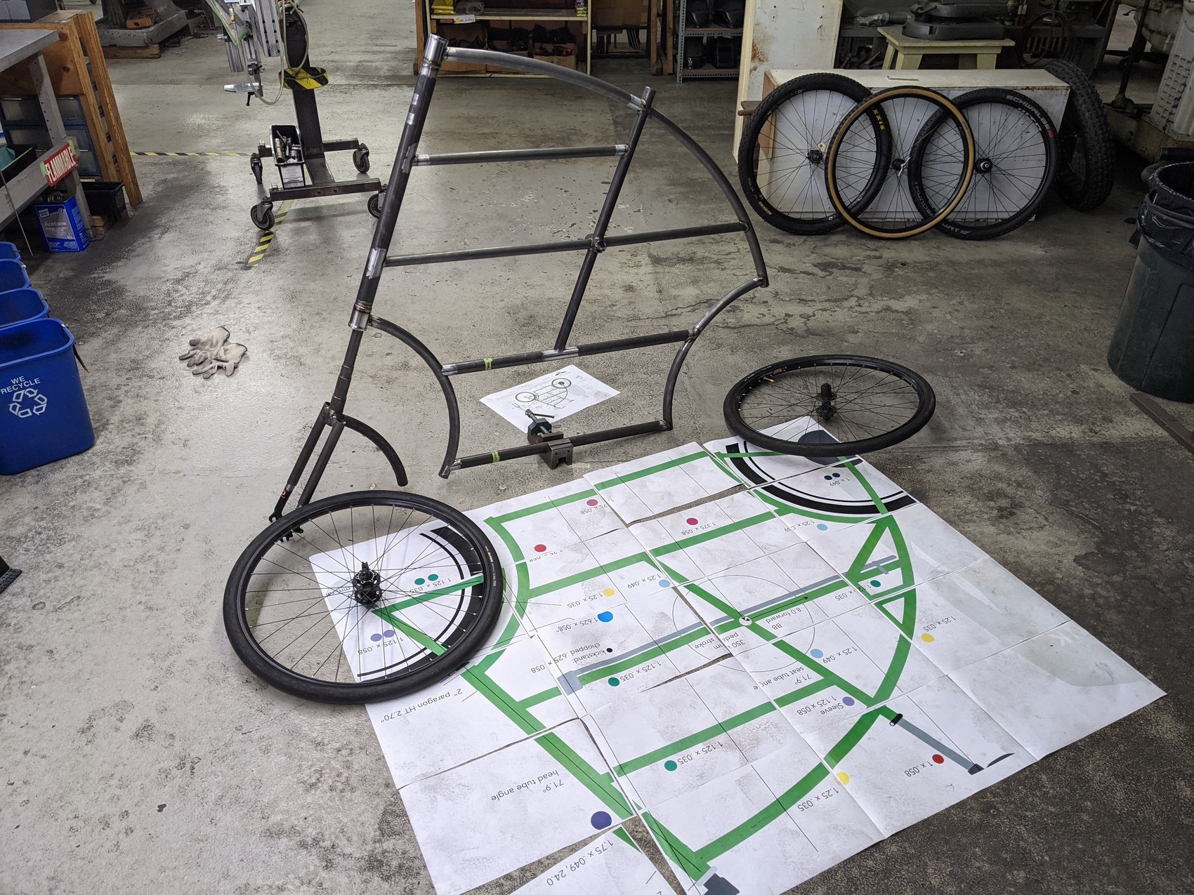 a tallbike frame stands on its own, with a life-sized blueprint lined up on the floor as if it were a shadow